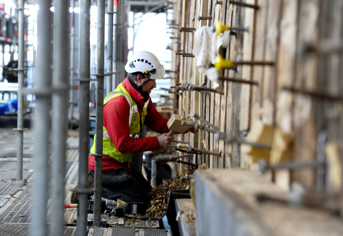 A shipwright in high visibility safety gear working on the hull of HMS Victory. 