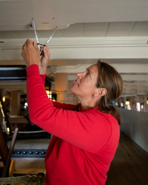 A conservator fixing a light fitting onboard HMS Victory. 