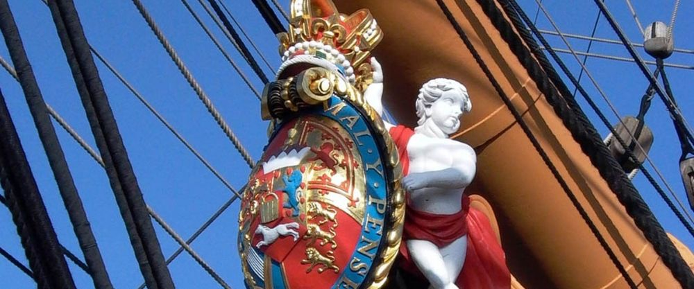 A replica of HMS Victory's original figurehead sits on her bow. 