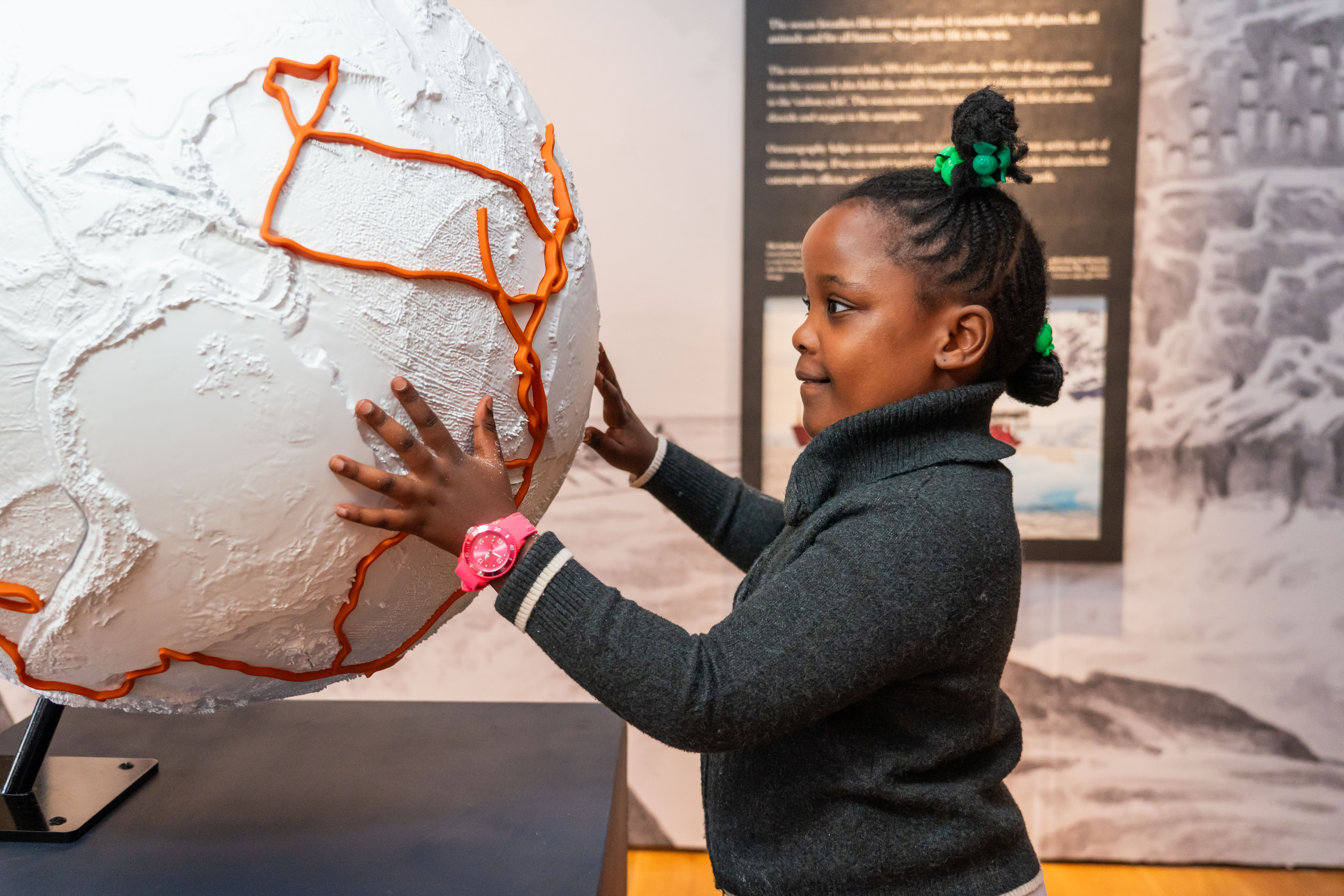 A young girl explores the World Beneath the Waves's Bathymetric Globe. 