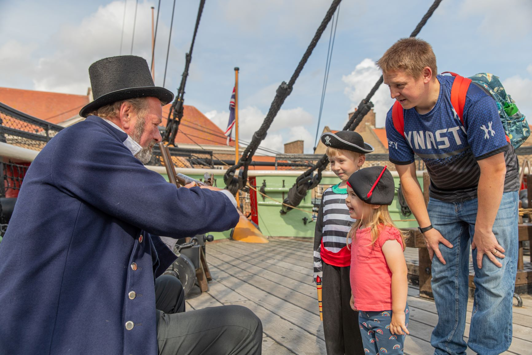 A costume interpreter giving a live weapon demonstration to a family.