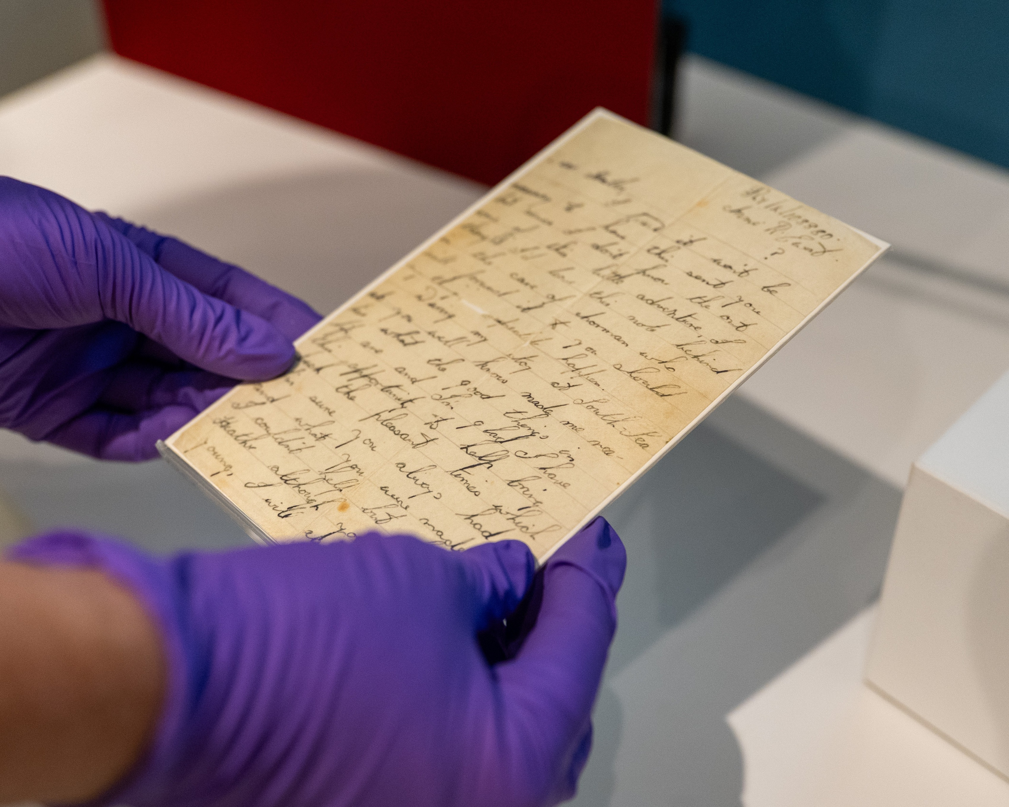 Curator in purple gloves holding a handwritten Operation Frankton farewell letter.