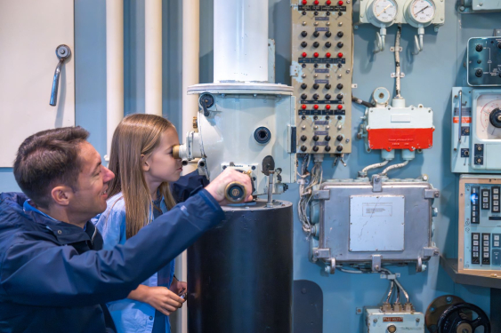 Father and daughter looking through a replica ship's periscope. 