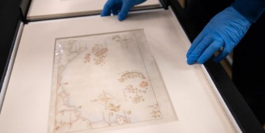 A conservationist examining one of the Armada Maps. 