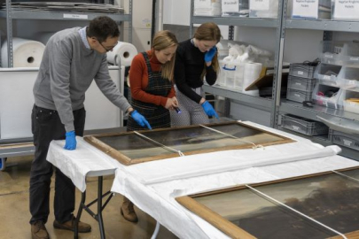 Curators from the National Museum of the Royal Navy looking at fine art from the collection.