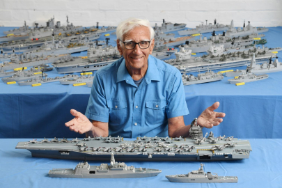 Phillip Warren sat in front of a model carrier made from matchsticks