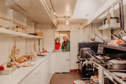 A couple look into an accurate recreation HMS Caroline's galley from the First World War.