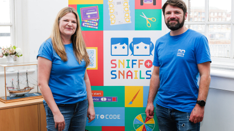 Sniff and Snails staff in front of banner with event resources.