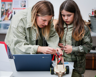 A mother and daughter building a small robot. 