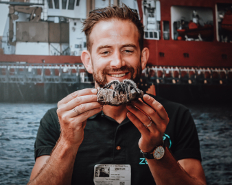A man holding up a tarantula on a piece of wood.