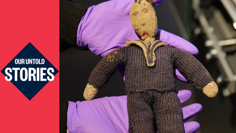 A knitted toy in the shape of sailor being held in purple gloves