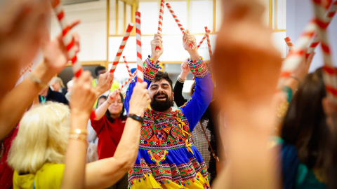 Performer in traditional dress leading a dandiya stick dance at the 'Diwali at the Dockyard' event