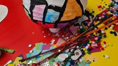 Craft materials including a decorated paper lantern, pipe cleaners, and pom-poms