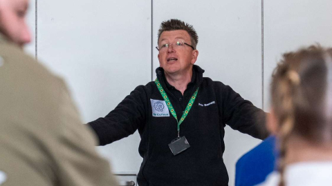 A museum educator with arms outstretched leading a session for children at the Home Educators ‘Reach an Island’ event