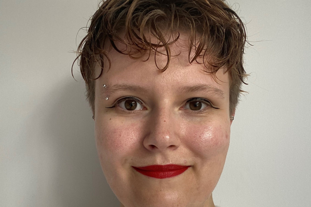 A young white woman with short red hair and red lipstick. 