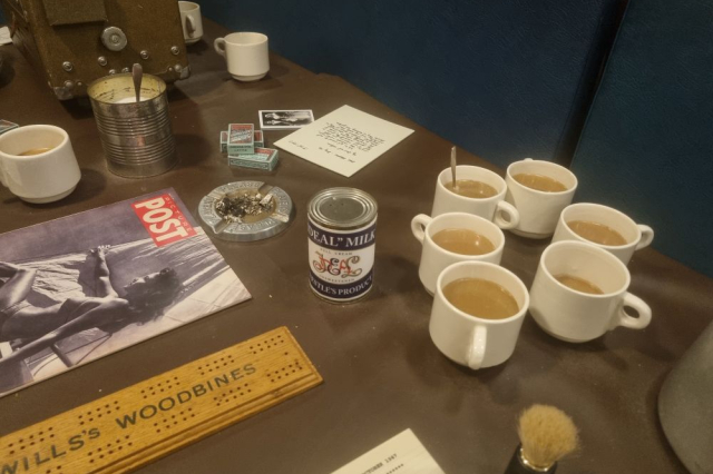 A mess table with milky cups of tea and a can of condensed milk on it. 