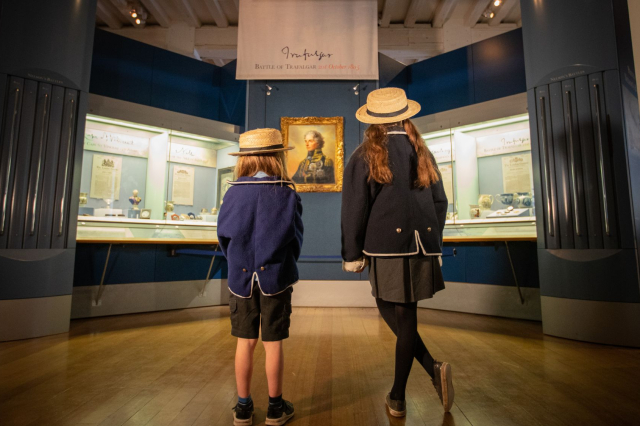 Two school children look at a portrait of Vice Admiral Lord Nelson. 