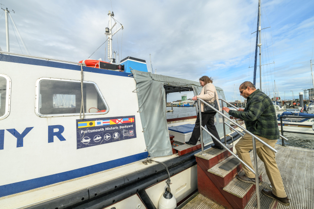 Two adults climbing a short set of stairs to board the waterbus. 