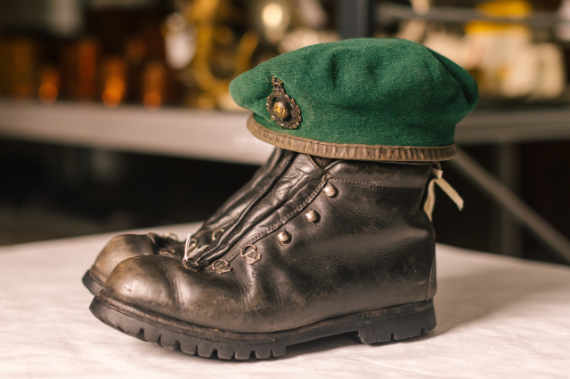 A Royal Marines green beret with cap badge resting on top of worn black leather boots