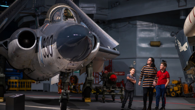 Mother and sons look up at a Royal Navy aircraft housed at the Fleet Air Arm Museum.