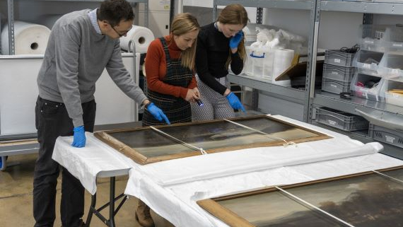 Curators from the National Museum of the Royal Navy looking at fine art from the collection.