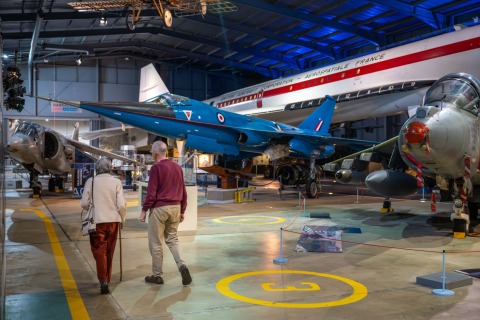 A couple walk through a hanger with Concorde 002 in the background. 
