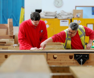 Two shipwrights woodworking in their workshop.  