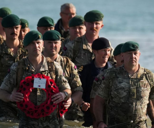 Royal Marines with a memorial walking on the beach. 