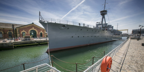 HMS Caroline, a first world war battleship, at dock in Belfast on a sunny day.