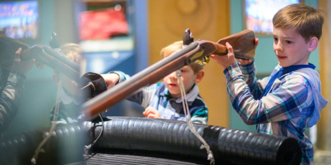 Children getting hands on with a gun display in the Hear My Story gallery.