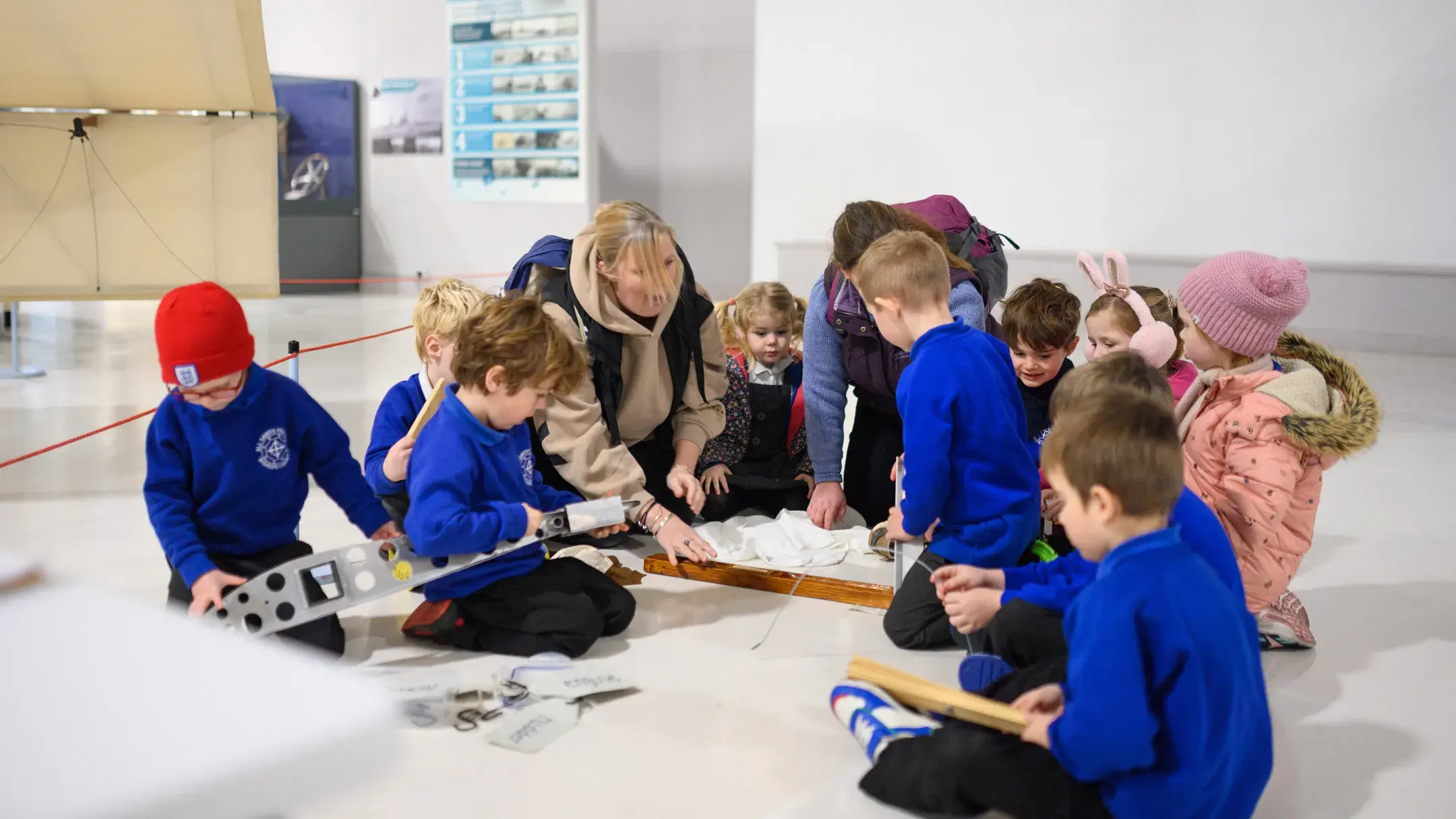 A group of infant school children looking at an original ship building tool.